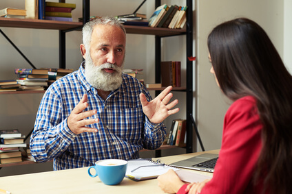 boss explaining something to young worker in his office